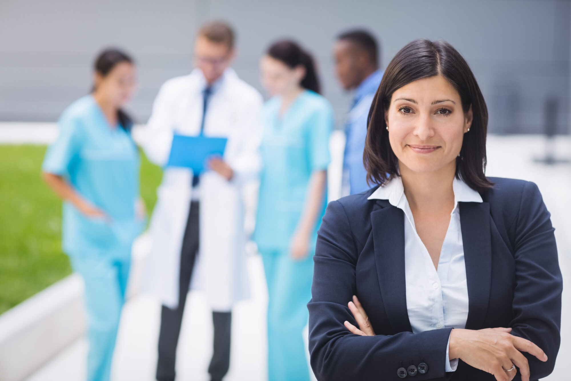 Portrait of smiling female doctor standing with arms crossed in hospital premises (About)